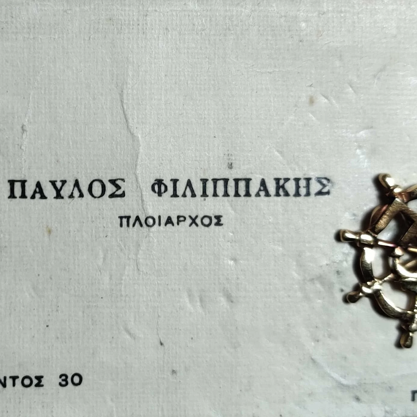 A vintage business card bearing the Greek name Pavlos Filippakis and the title Captain, beside a cross