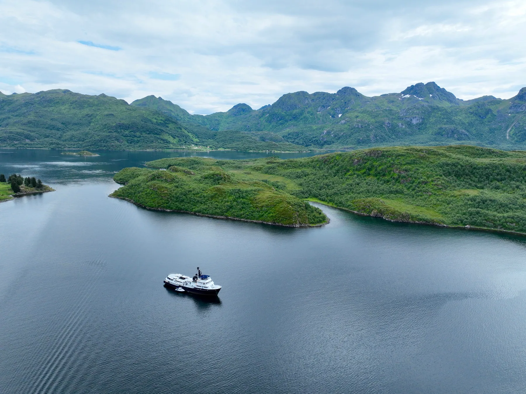 Aerial view of an explorer yacht at anchor in a green Lofoten fjord